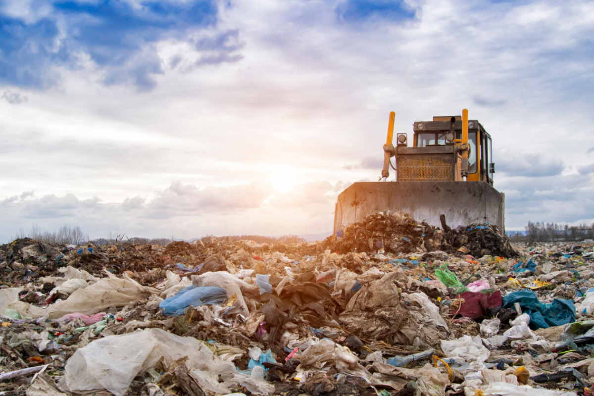 bulldozer working on landfill with birds in the sky.